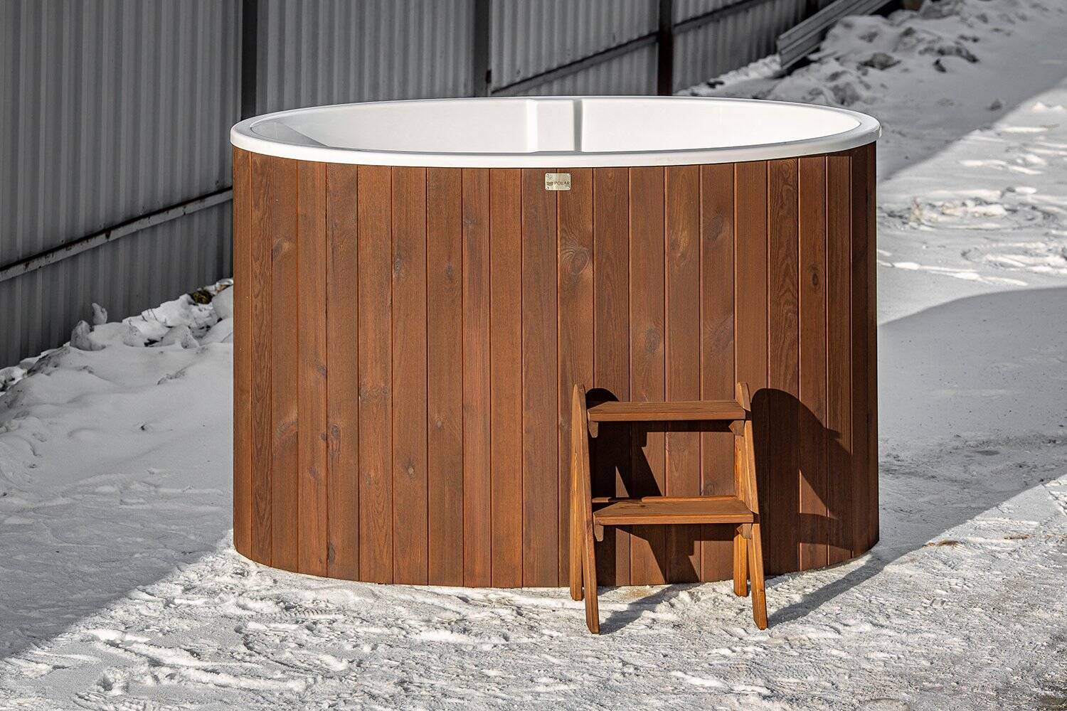 Outdoor cold plunge tub beside a garden sauna