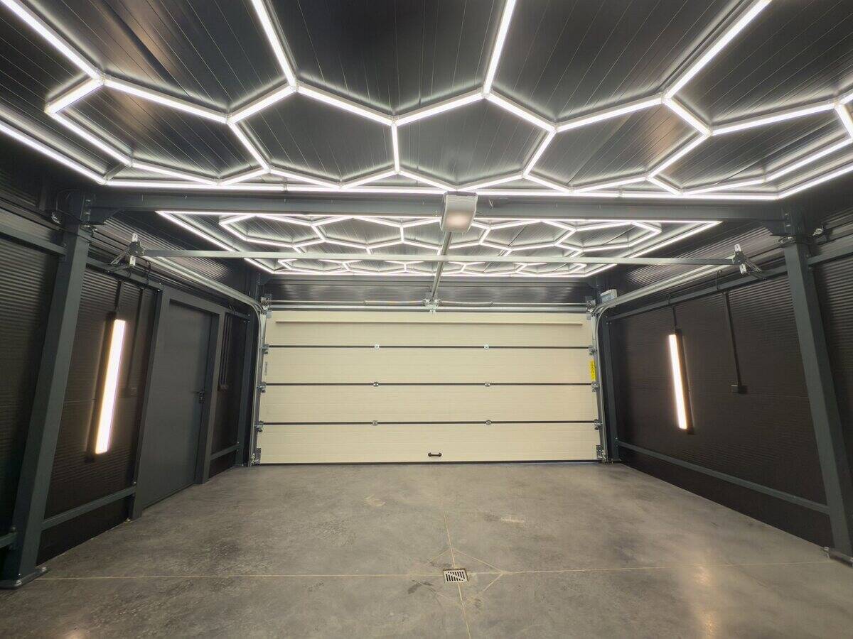 Insulated garage interior with hexagonal LED ceiling lighting and white PIR wall panels