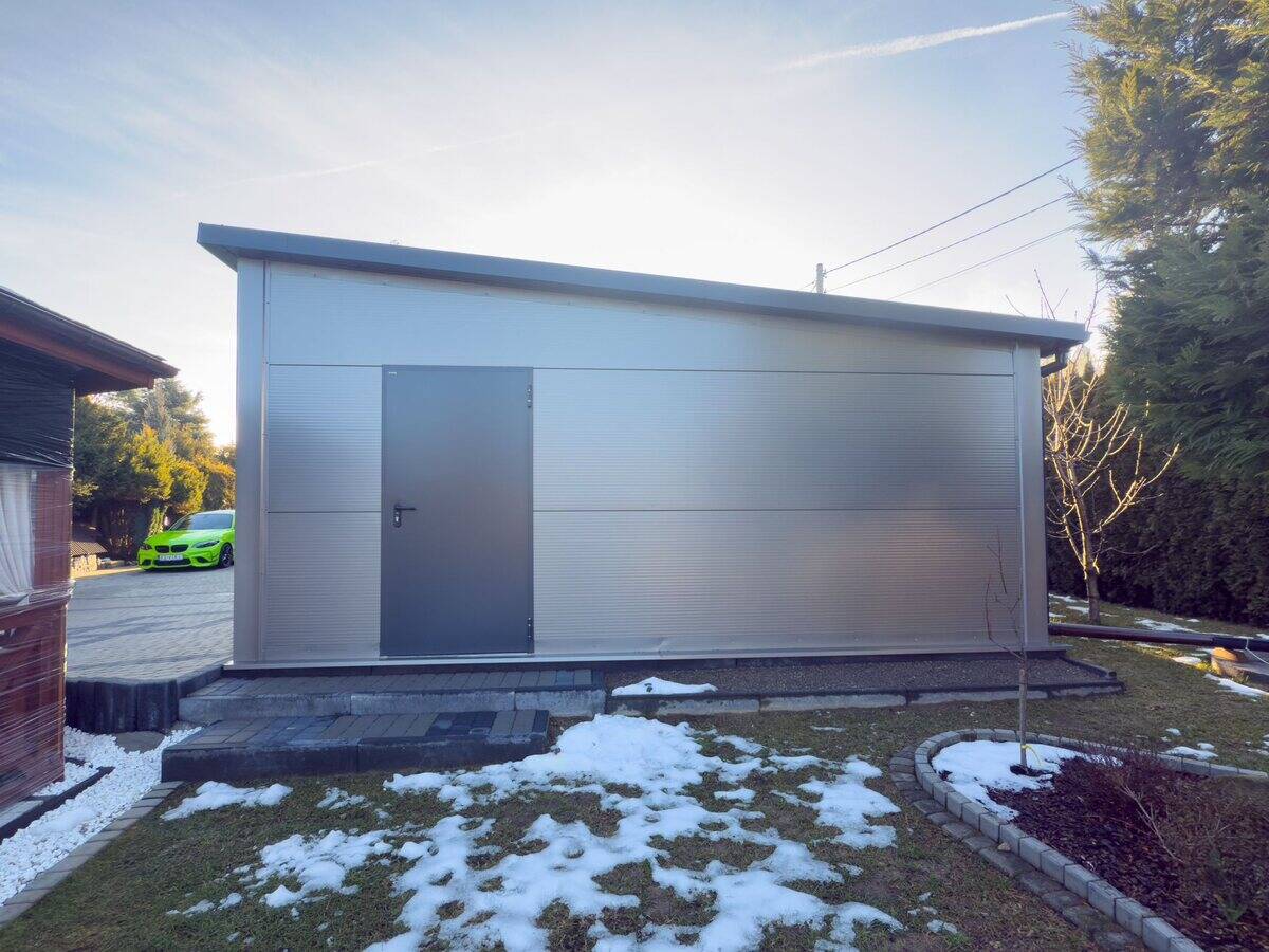 White-walled insulated PIR garage in winter with snow, anthracite sectional door and side window