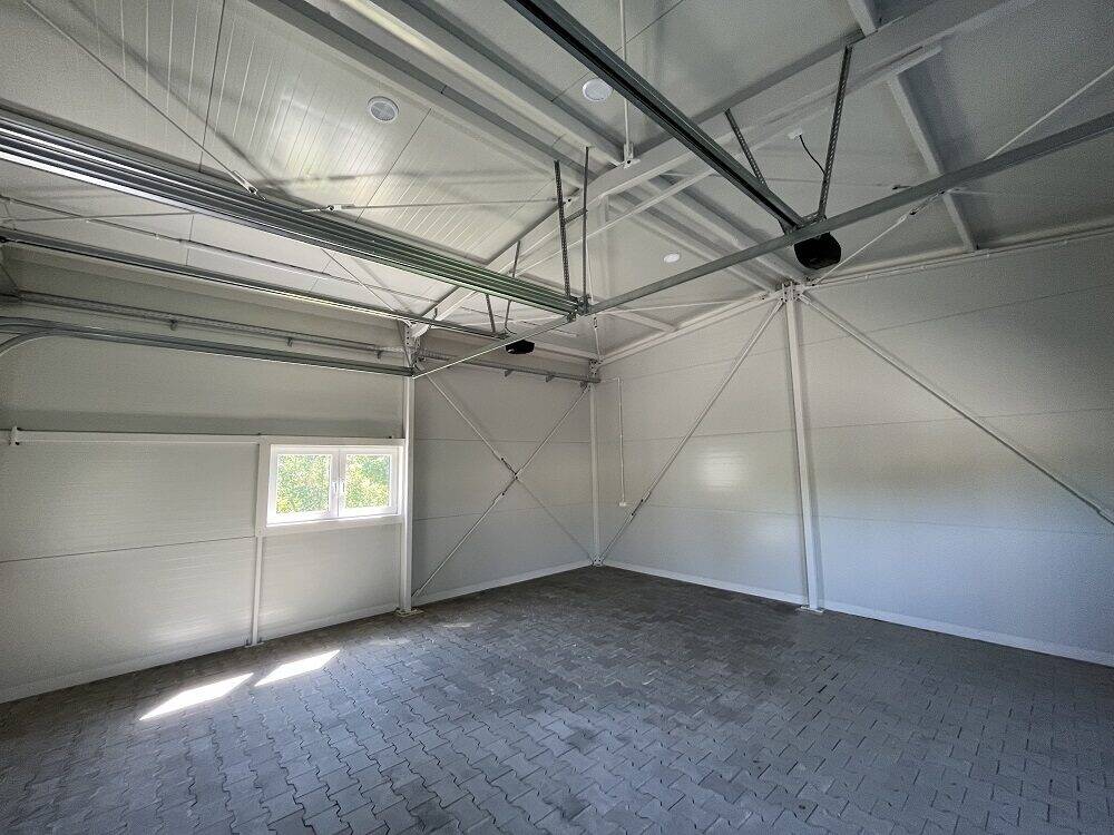 Insulated garage interior with white PIR panels and a side window, paved floor