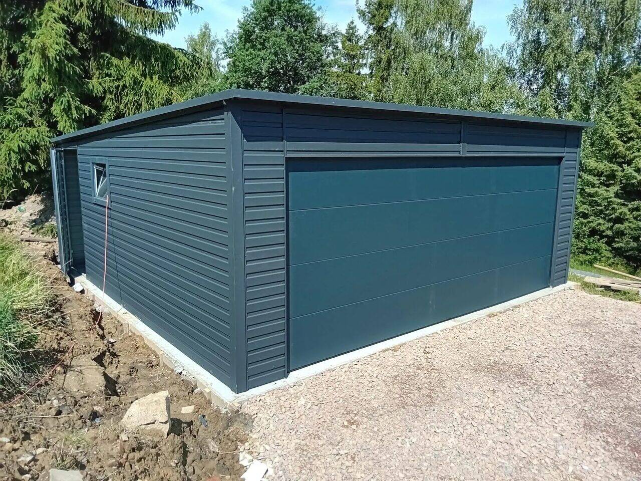 Anthracite steel garage, front-right three-quarter view showing the ribbed side wall and insulated side door