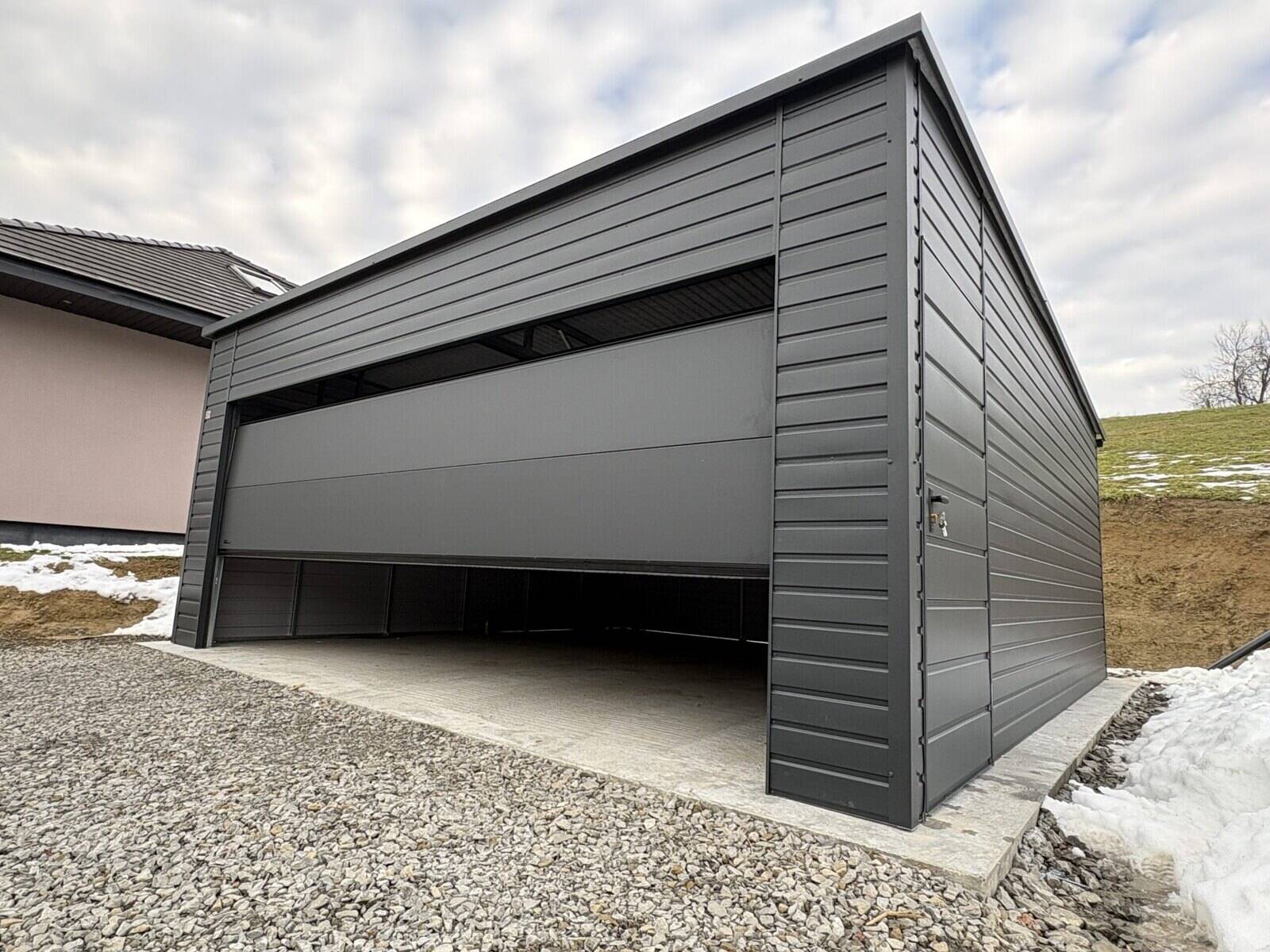 Anthracite steel garage, three-quarter view in a rural setting